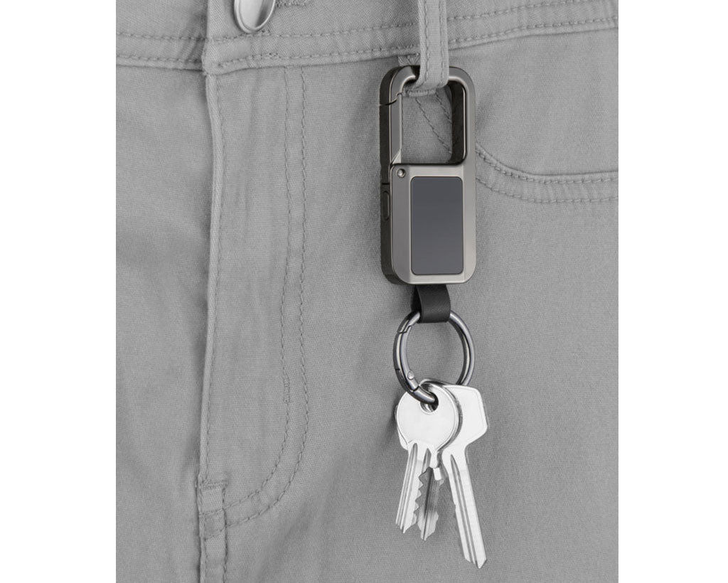 Troika TRACK & FIND CARABINER" gunmetal - KR26-13/GM, with "Apple Find My" - and keys clipped to the waistband of light gray pants, holding two silver keys on a key ring.