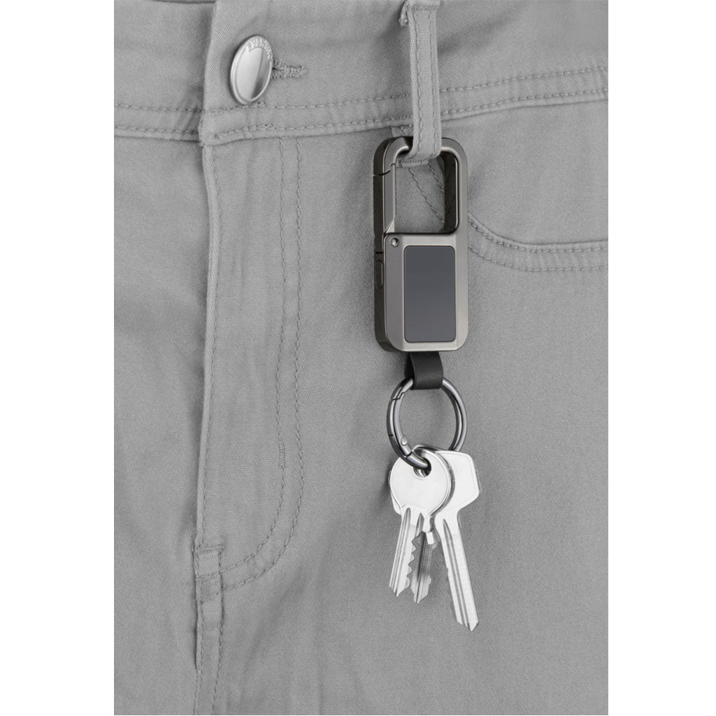 Troika TRACK & FIND CARABINER" - gunmetal, with "Apple Find My" -  and keys clipped to the waistband of light gray pants, holding two silver keys on a key ring.