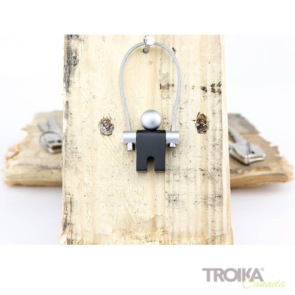 TROIKA JUMPER keychain - black athletic figure charm on wooden board